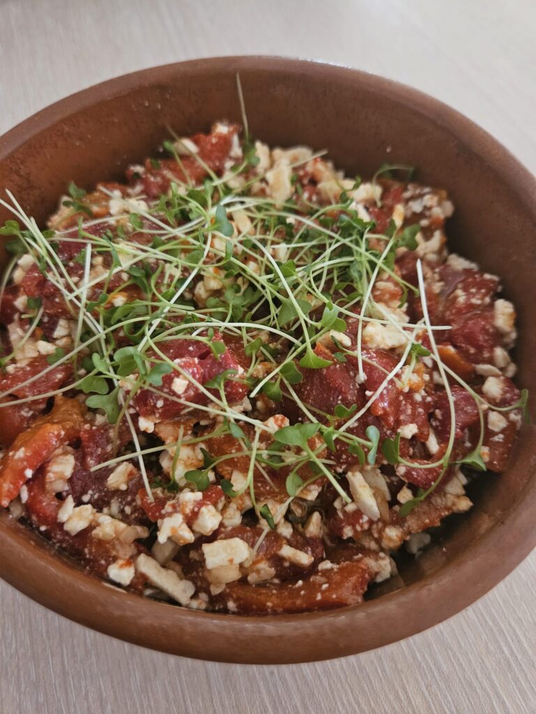 A close-up of Fermented Red Pepper and Goat Cheese Mix showing creamy cheese and red pepper pieces.