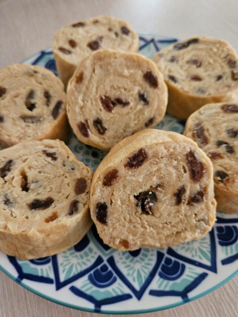 Sliced wafer rolls with raisins arranged on a plate, photographed close up.