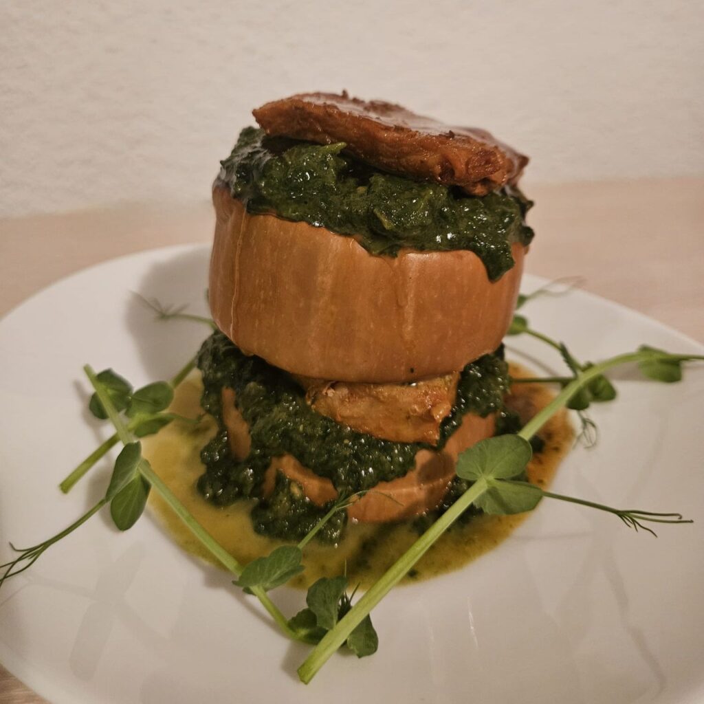 A beautifully arranged Butternut Chard Pork Stack showing layers of roasted butternut, chard with garlic, and tender pork slices on a plate.