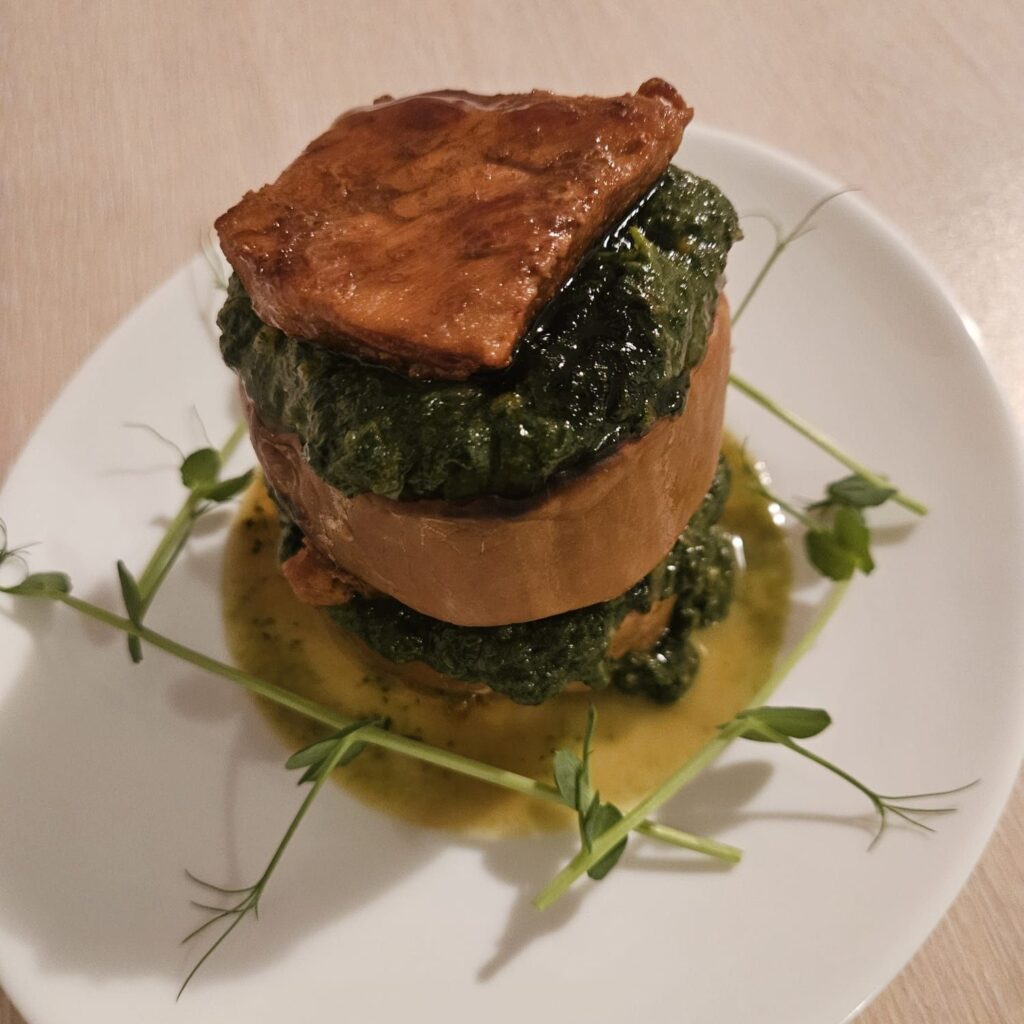 A close-up view of Butternut Chard Pork Stack showing layered roasted butternut, chard with garlic, and tender pork slices on a plate.