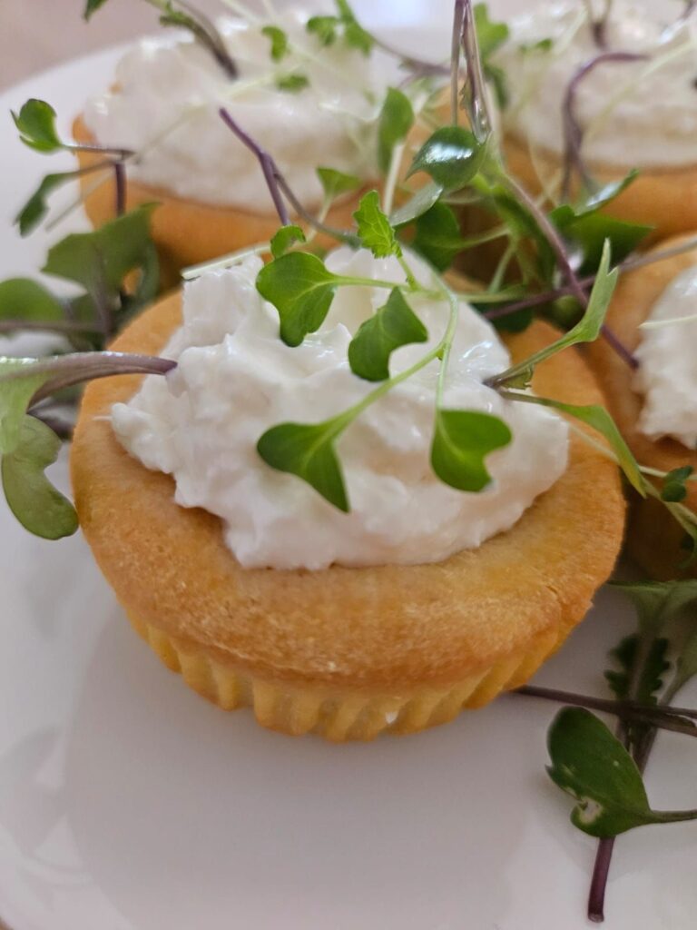 Close-up of Cornmeal Tartlets with Goat Cheese and Microgreens served on a plate.