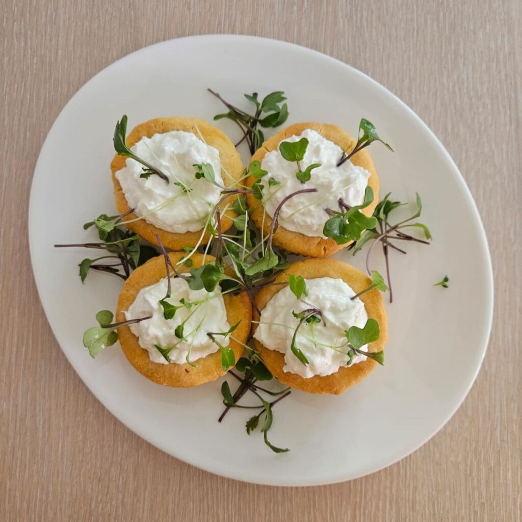 Four Cornmeal Tartlets with Goat Cheese and Microgreens beautifully served and garnished with microgreens.