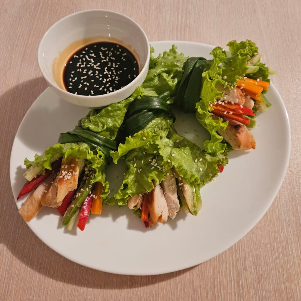 Chicken and vegetable wraps in lettuce leaves served with soy and honey sauce.