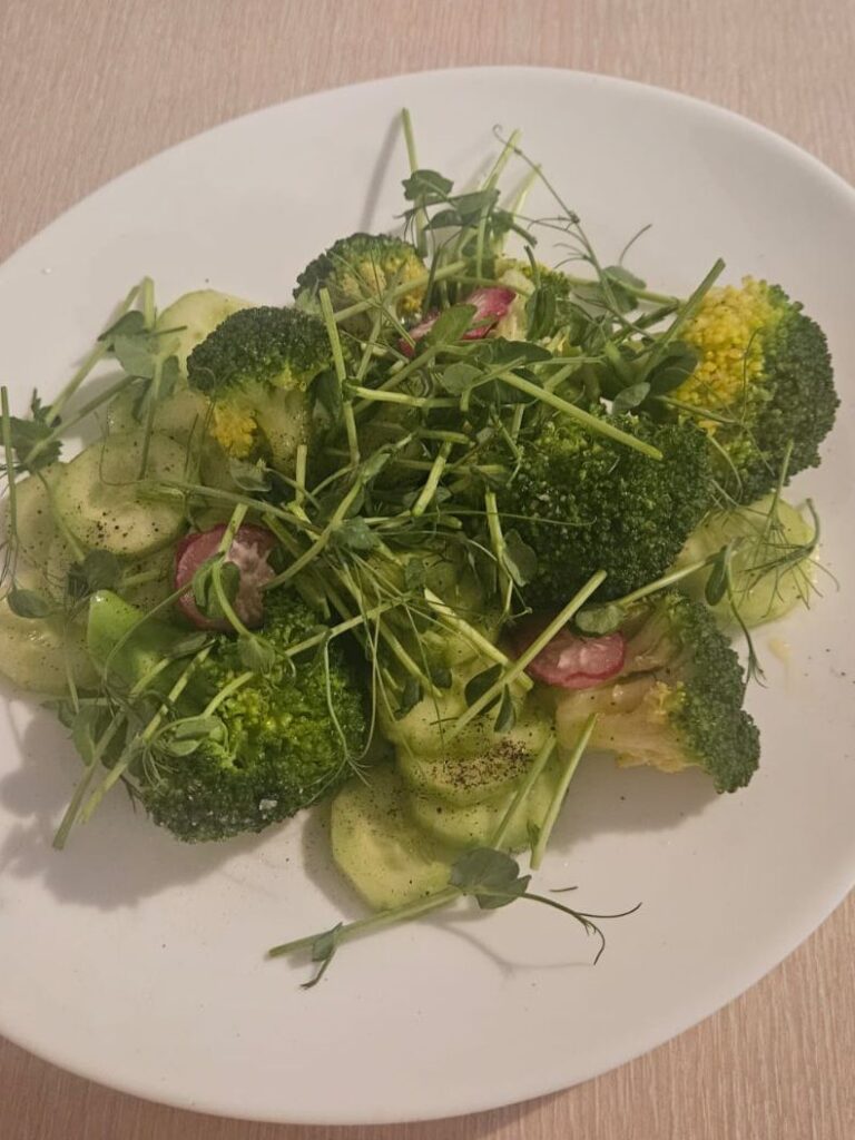 Close-up of fresh vegetable salad in a white plate with colorful greens.