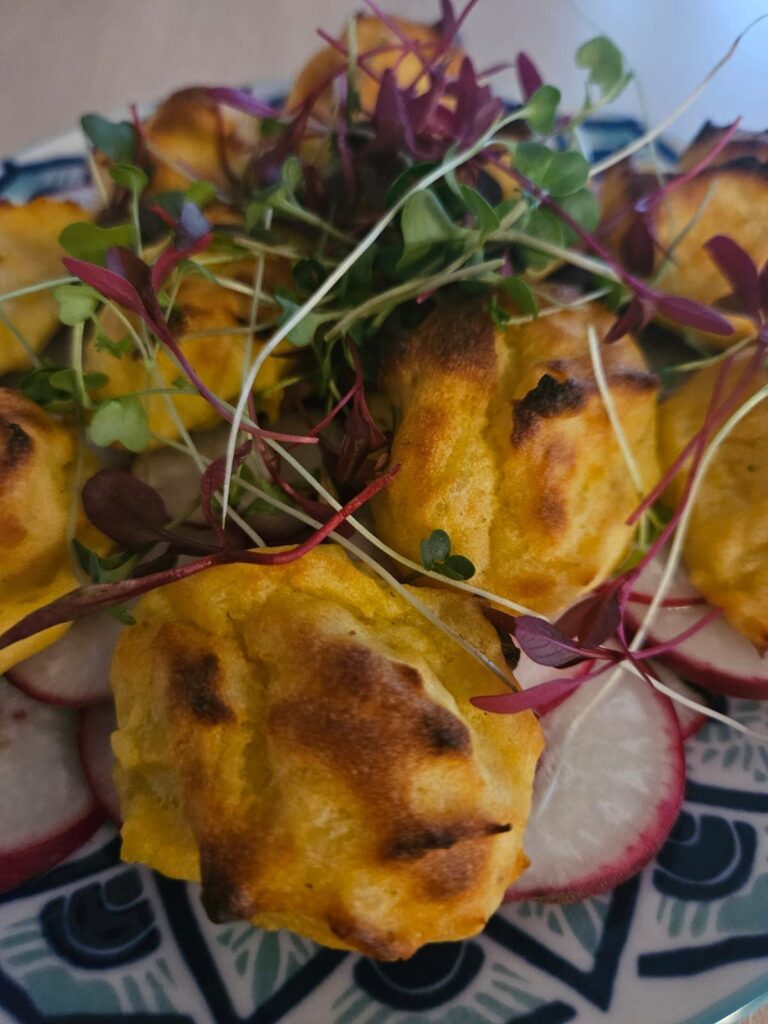 Golden potato balls served with thinly sliced radishes and fresh microgreens for a rustic homemade look.