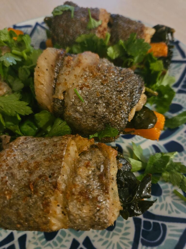 Close-up view of Fish Rolls with Carrot and Spinach served on a colorful flat plate.