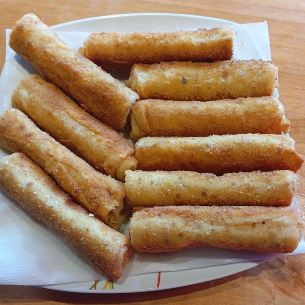 Golden crispy ham crepe rolls served on a large flat plate, ready to enjoy.