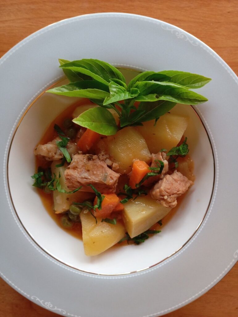 Close-up of Beef Pea Potato Stew served in a wide, deep plate, showing tender beef, peas, and potato pieces.