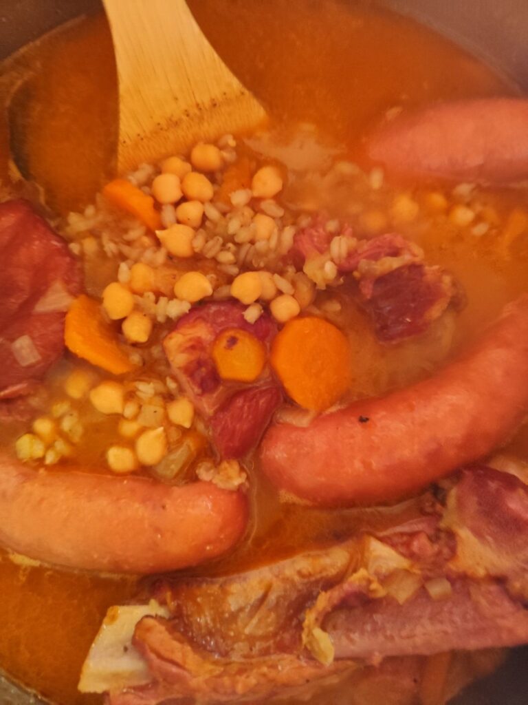 Barley and whole sausages added to the simmering stew with smoked pork and vegetables.