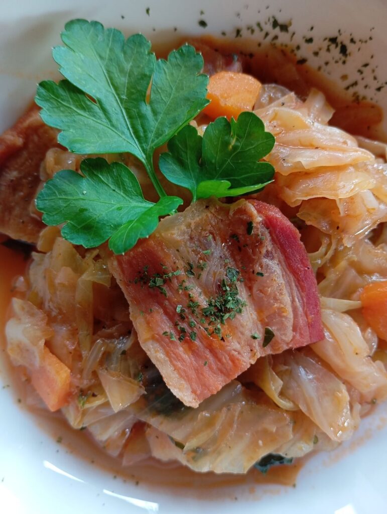 Close-up of a deep bowl filled with Savory Cabbage Pancetta Stew, showing tender cabbage and crispy pancetta.