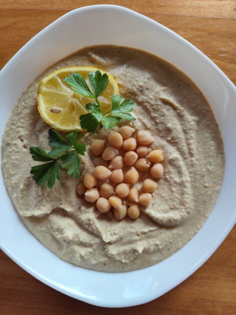 Close-up of creamy chickpea spread served in a deep bowl, showing smooth texture and rich color.