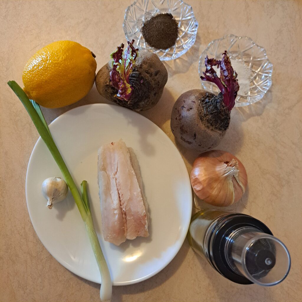 Ingredients for Fish Fillet Beetroot Mash including beetroot, fish fillet, lemon, garlic, green onion, olive oil, salt, and pepper on a kitchen table.