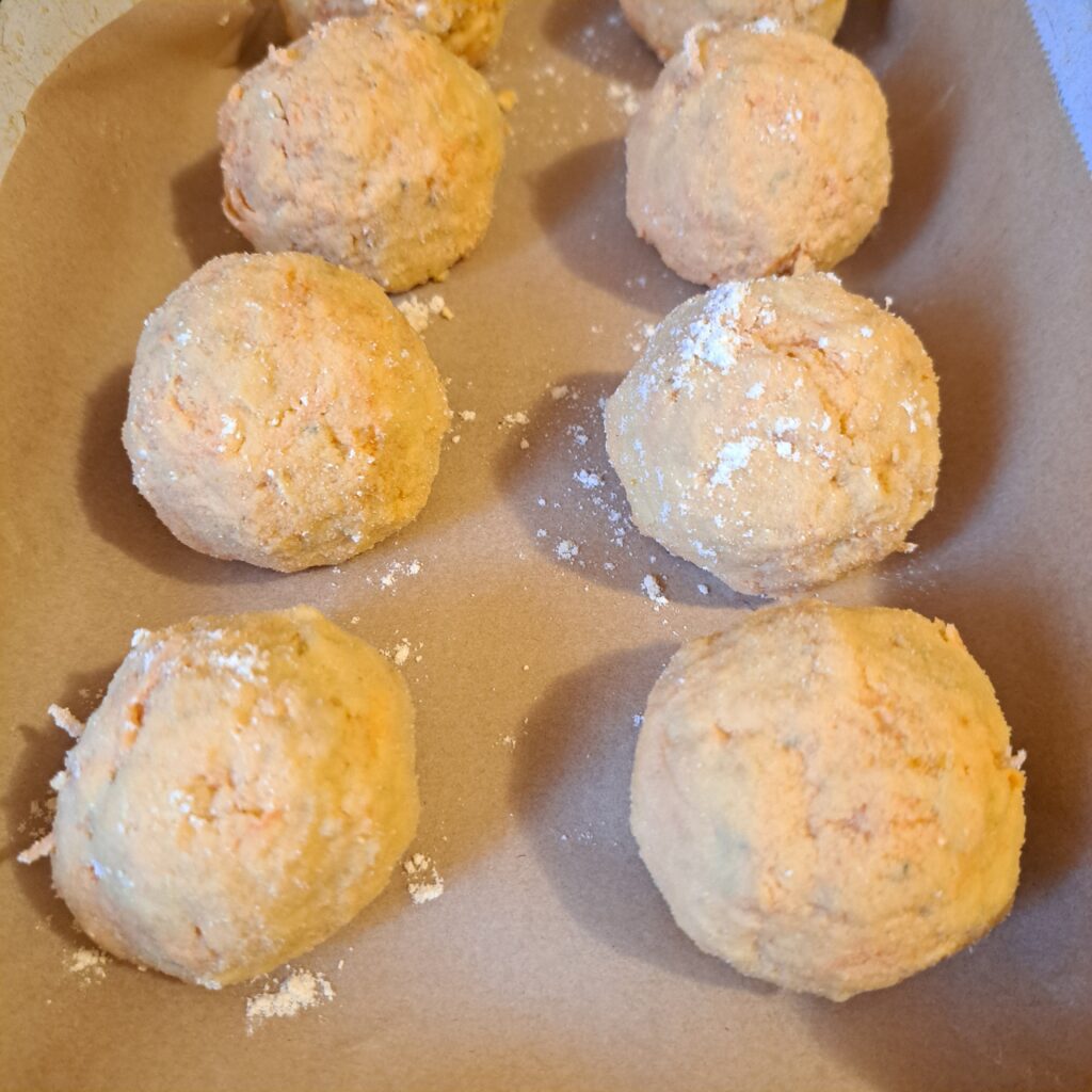 Unbaked Sweet Fish Dill Bites placed on parchment paper in a baking tray, ready for the oven.