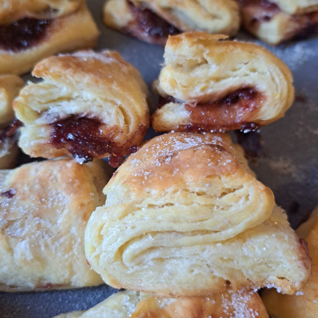 Flaky lard homemade pastries baked to a golden finish and dusted with vanilla sugar in a buttered baking pan.