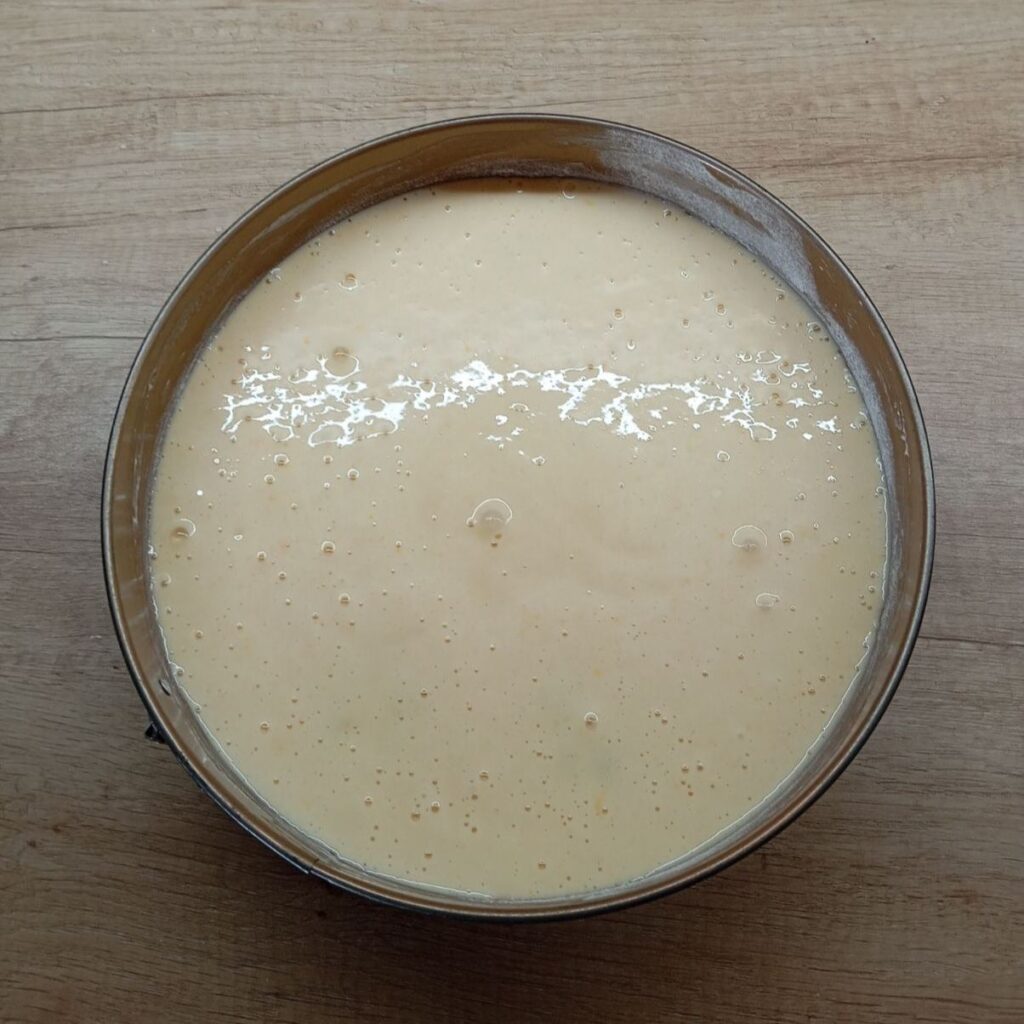 Batter being poured over the arranged mandarins in the baking pan.