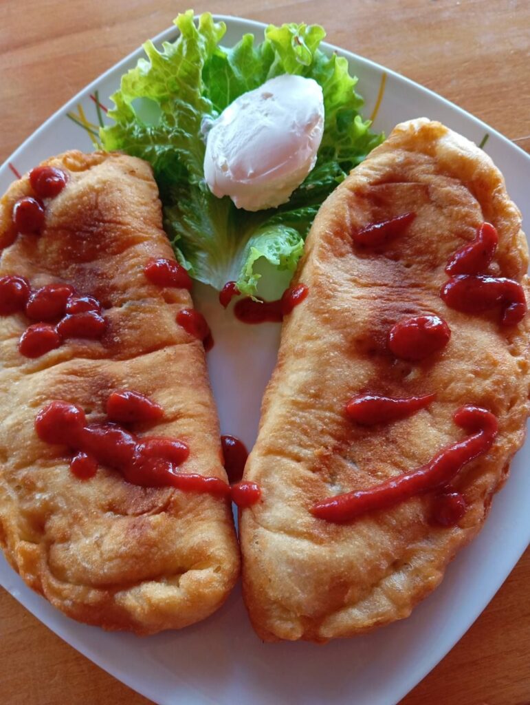 Close-up of two folded ham pizzas, golden and crispy, served in a white plate.