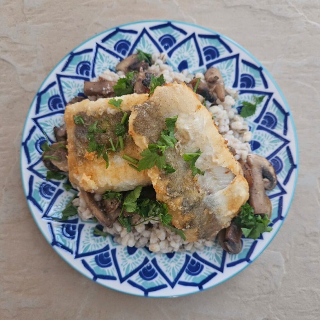 Seared Fish Mushroom Barley beautifully served on a colorful plate, garnished with chopped parsley.