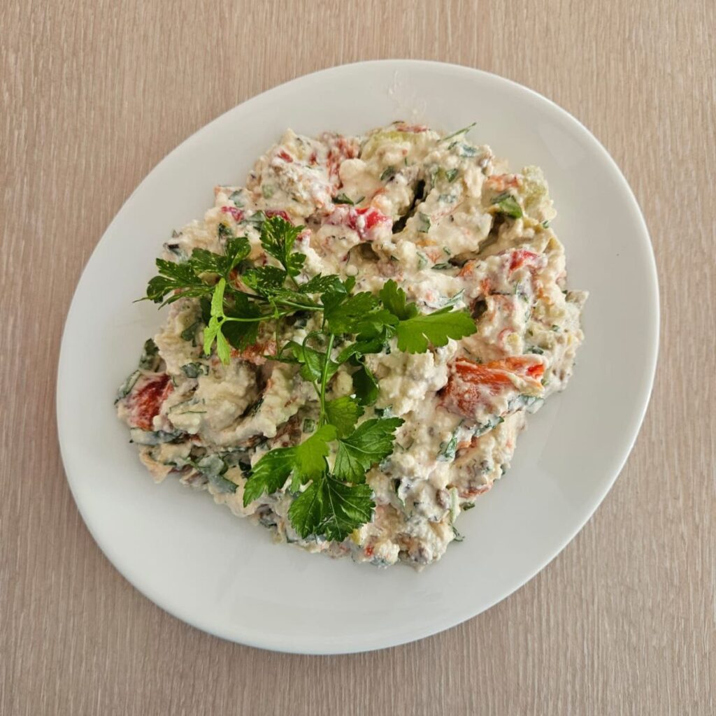 Roasted Peppers Walnut Salad served in a white shallow plate, garnished with parsley sprigs.
