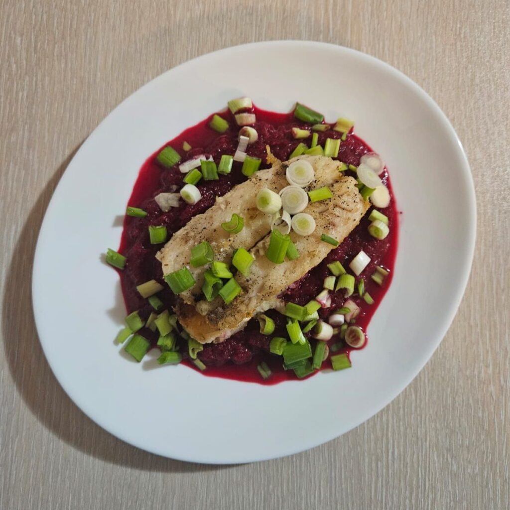Fish Fillet with Beetroot Mash served with chopped green onion as garnish.