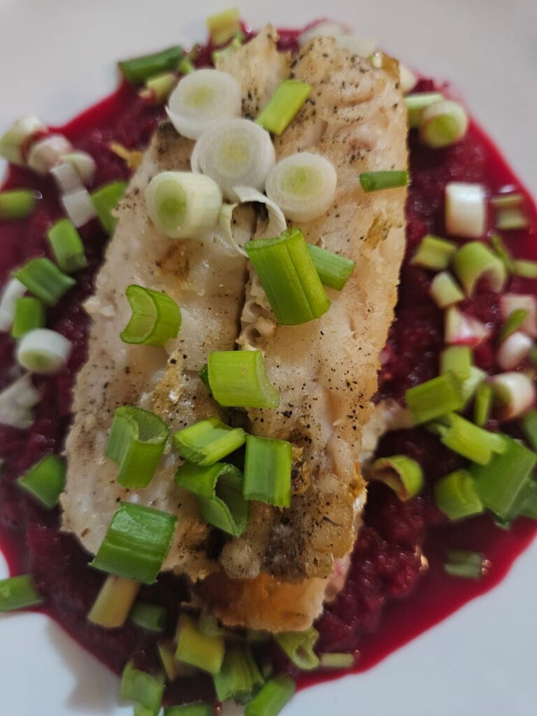 Close up of fish fillet served with creamy beetroot mash on a plate.