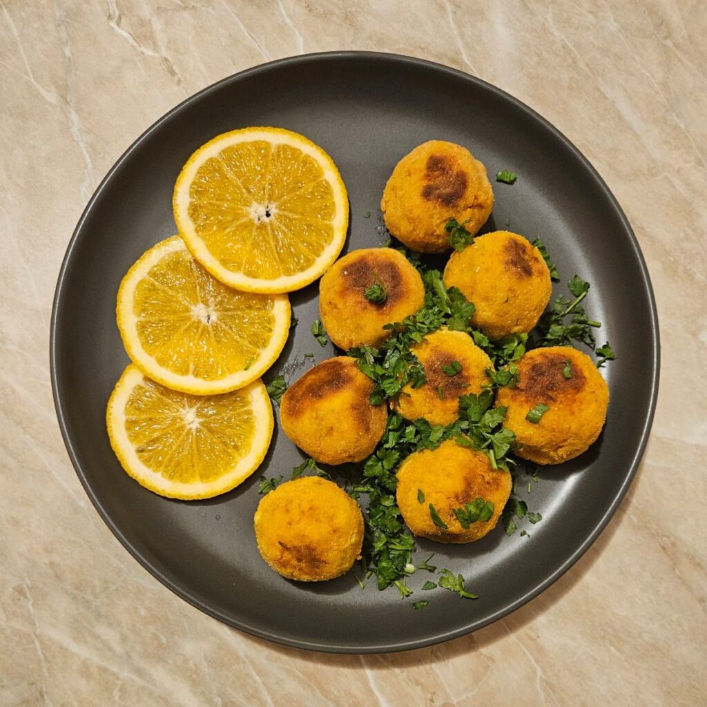 Sweet Fish Dill Bites decorated with chopped parsley and orange slices on a plate.