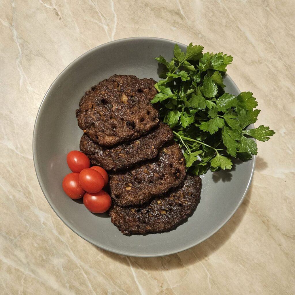 Served Pork Liver Potato Patties arranged on a plate with whole cherry tomatoes and a small bunch of parsley.