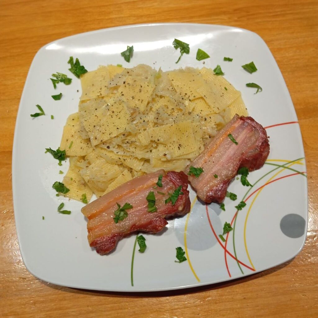 Top-down view of Bacon Cabbage Pasta Squares on a plate, showing pasta squares mixed with cabbage and topped with crispy bacon and chopped parsley.
