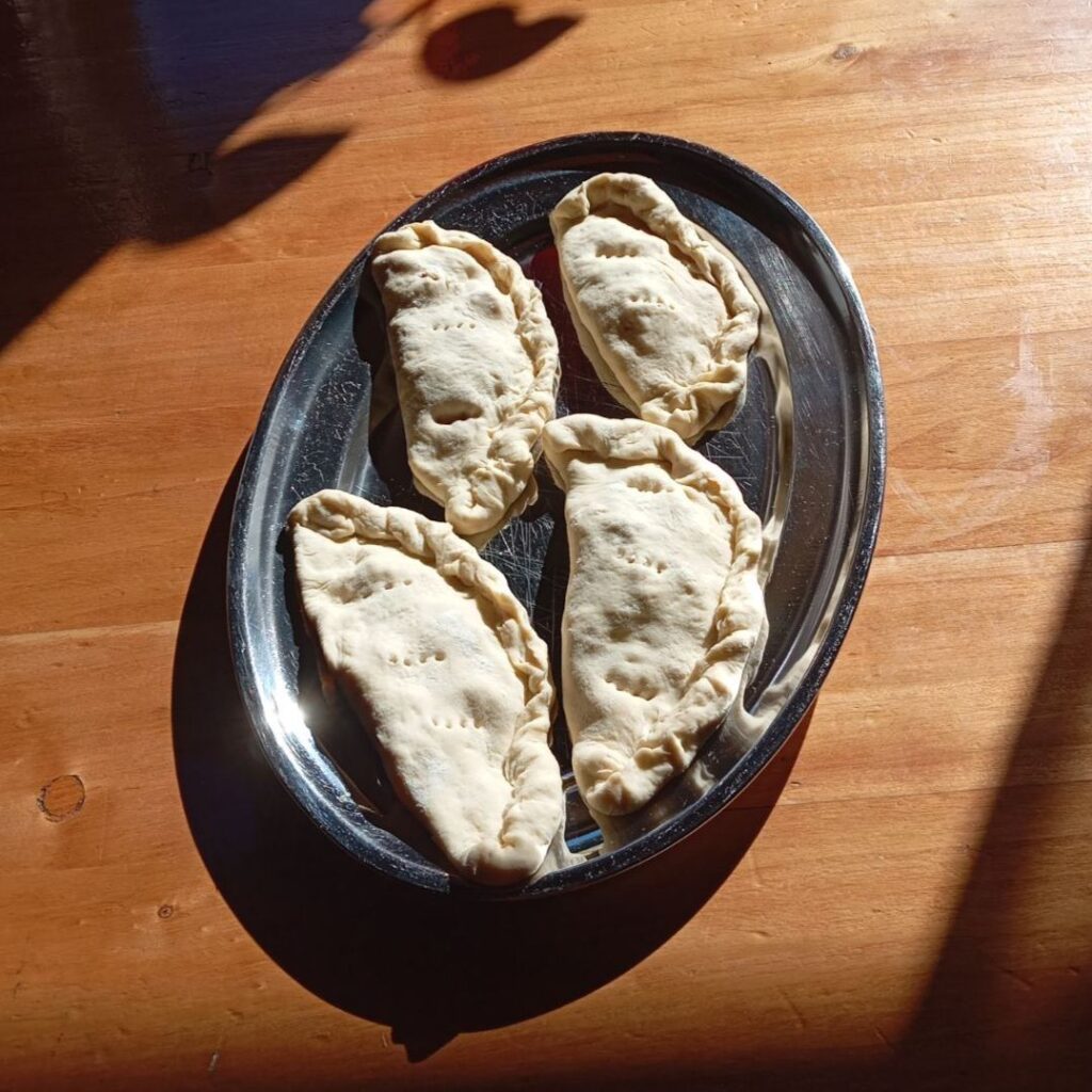 Folding each pizza into a shell shape and sealing edges to keep the filling inside before frying.