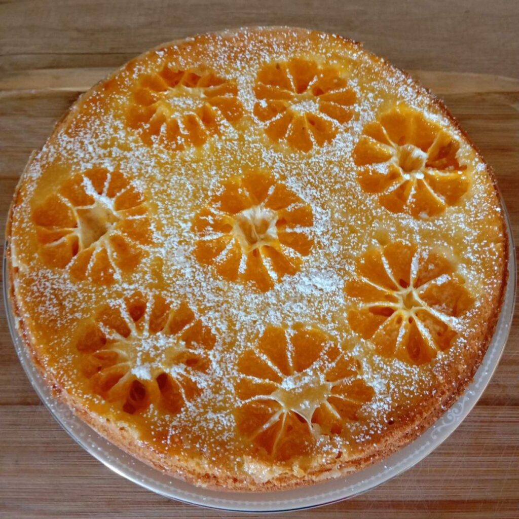 Whole Simple Juicy Mandarin Cake topped with powdered sugar, ready to serve.