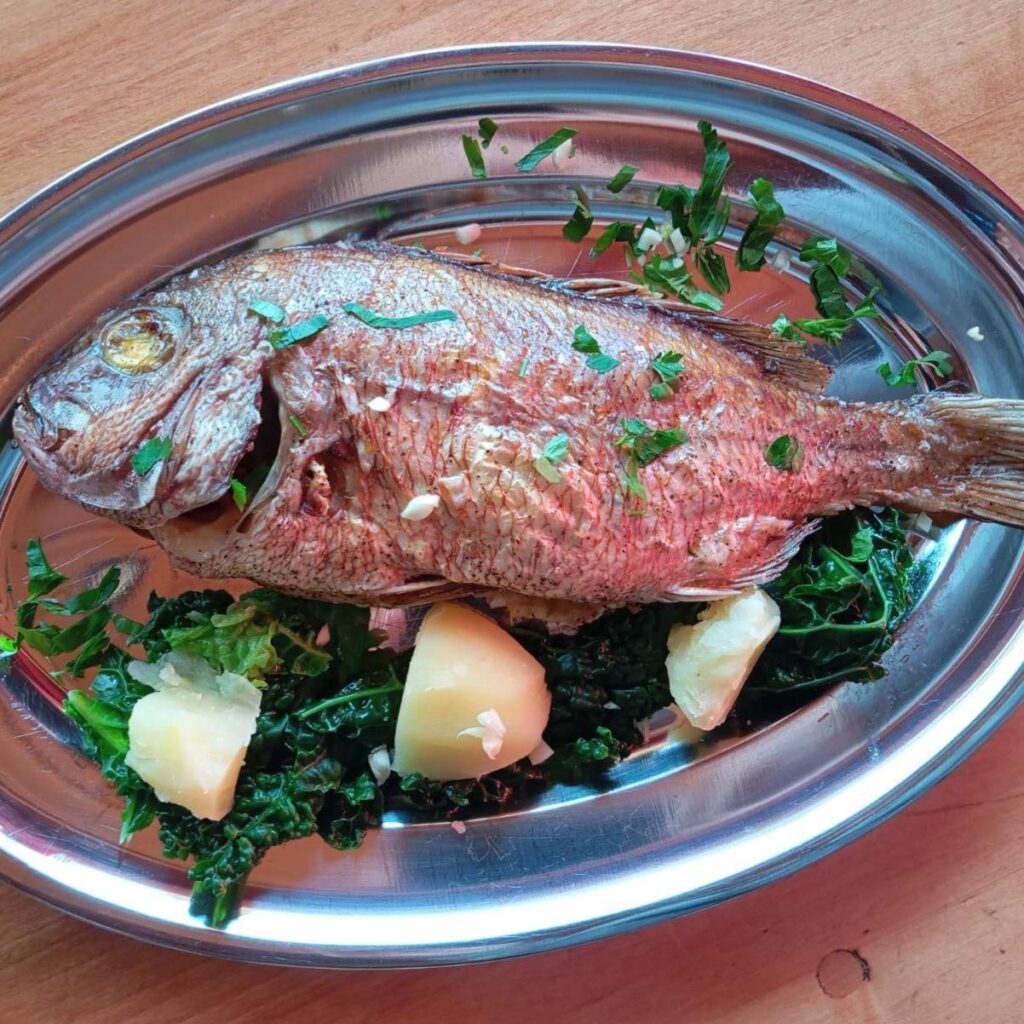 Served Baked Red Seabream Delight with boiled potatoes, kale, and finely chopped parsley arranged on a plate.