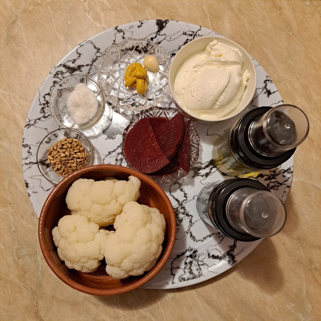 Ingredients for Beet Cauliflower Creamy Salad arranged on a plate, including cauliflower, beetroot, sour cream, and seasonings.