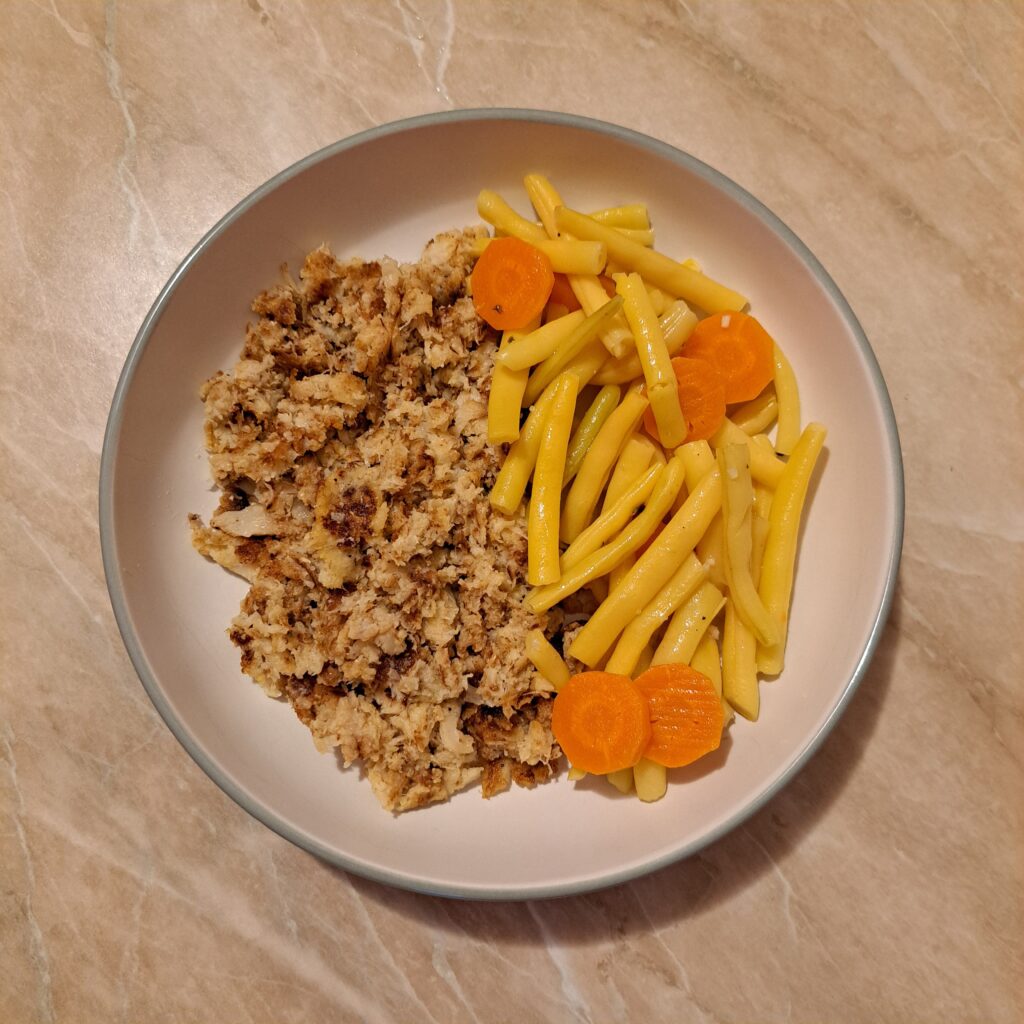 Green beans with carrot and prepared cauliflower arranged together on a plate before adding the pork schnitzel and sauce.