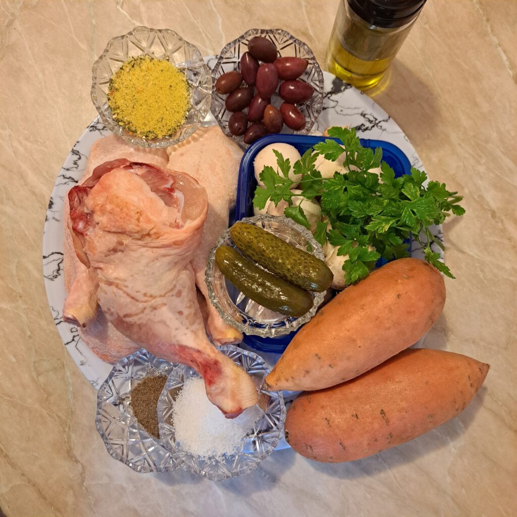 Ingredients for Juicy Chicken Veggie Plate including whole chicken legs, sweet potatoes, mushrooms, olives, pickles, garlic, parsley, salt, black pepper, and mixed seasoning.