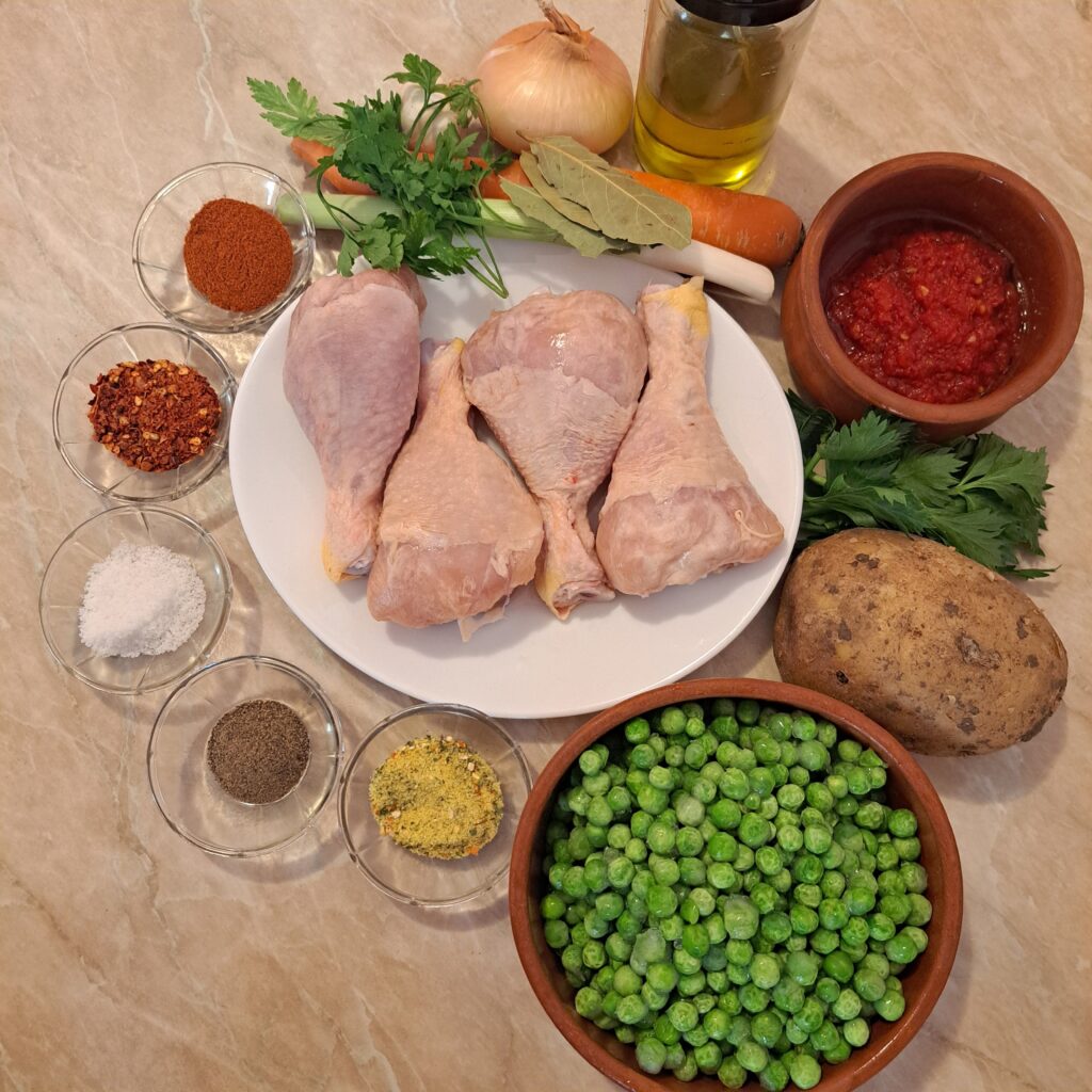 Ingredients for Chicken Drumstick Pea Stew arranged on a kitchen counter, including peas, chicken drumsticks, vegetables, seasonings, and oil.