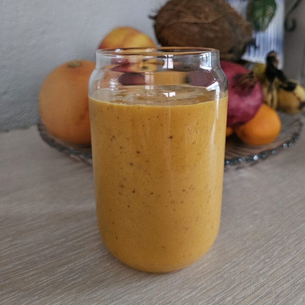 A creamy orange Persimmon Butternut Cranberry Smoothie made with persimmon, butternut squash, and dried cranberries, served in a clear glass.