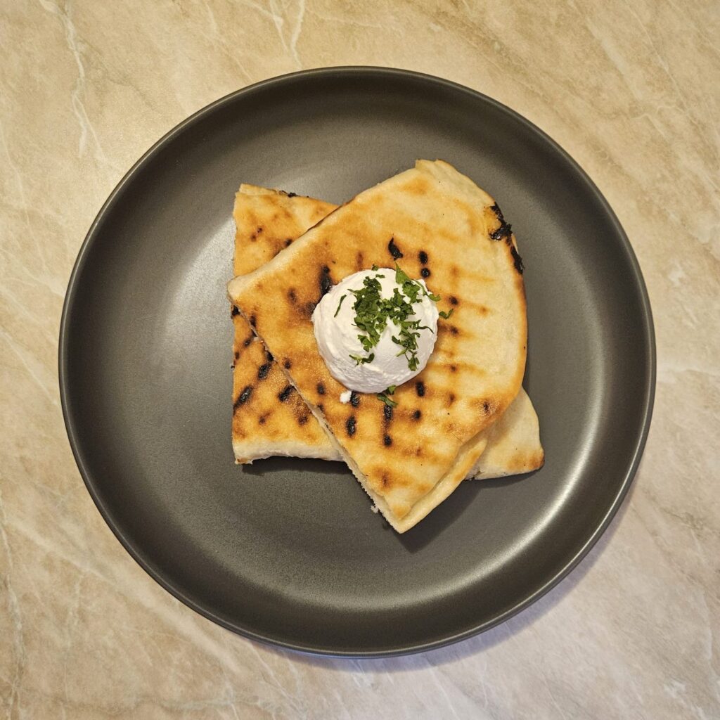 Two halves of Creamy Chicken Grill Flats served with a scoop of sour cream and chopped fresh parsley.