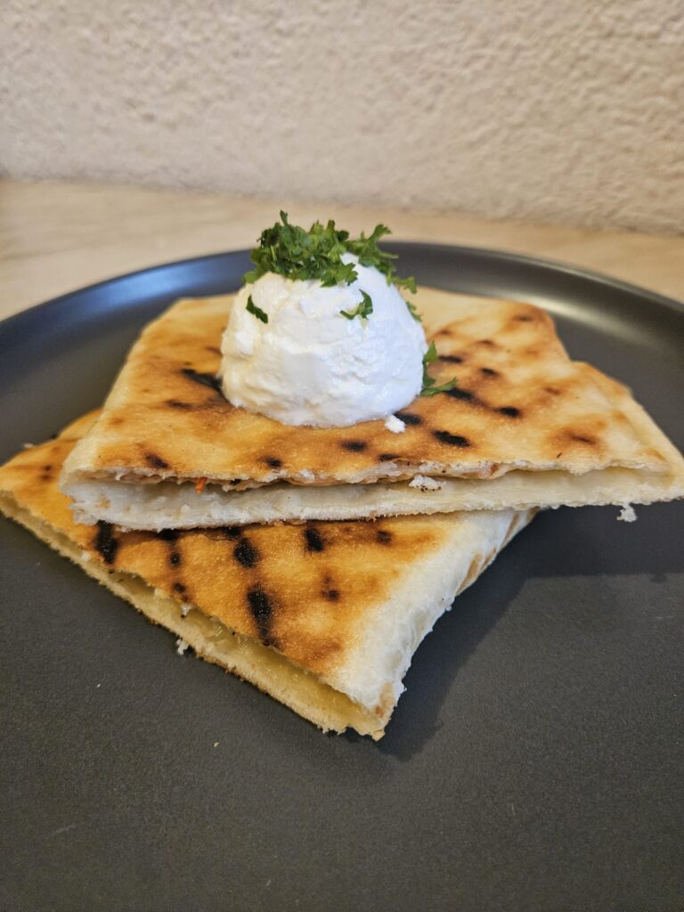 Close-up of a Creamy Chicken Grill Flat cut in half, served on a plate, showing creamy chicken filling and golden grilled dough.