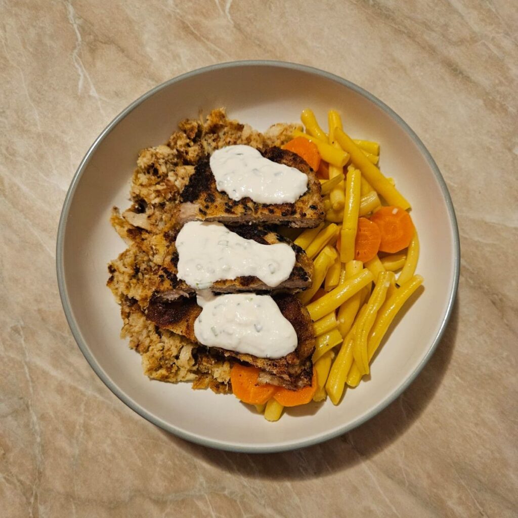 Fully served Crispy Pork Veggie Plate with sliced pork schnitzel placed over vegetables and finished with sour cream and mayonnaise sauce.