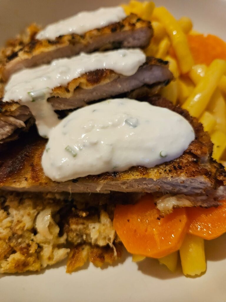 Side view of the Crispy Pork Veggie Plate showing sliced breaded pork schnitzel, cooked green beans with carrot, and fried cauliflower pieces.