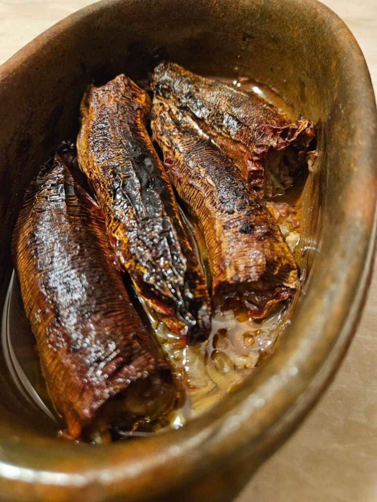 Close-up of meatless stuffed dried peppers served in a small oval ceramic baking dish.