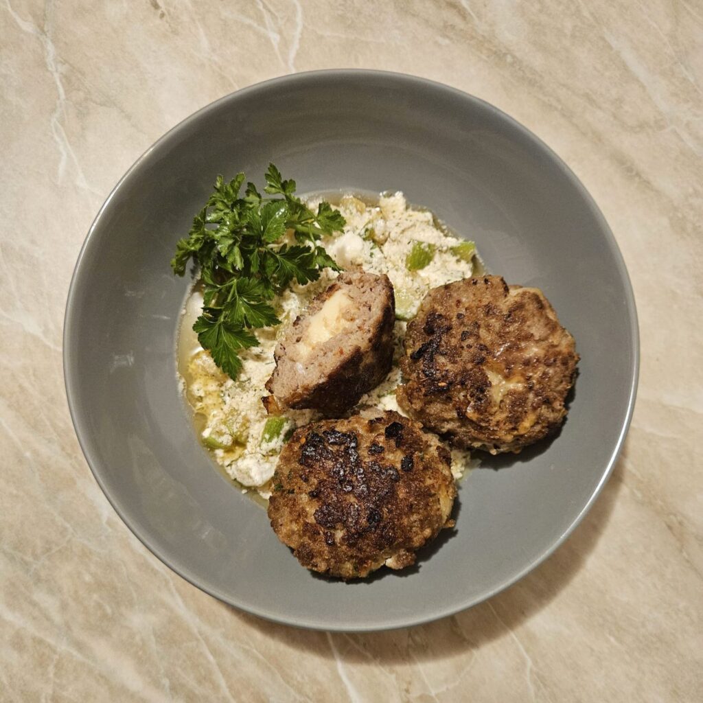 Plate of Meat Patties Zucchini Cream, showing golden patties on slightly watery zucchini cream, garnished with fresh parsley.