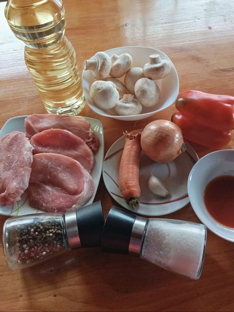 Ingredients arranged on a table for Braised Pork Vegetables Dish, including boneless pork loin chops, mushrooms, bell pepper, carrot, onion, garlic, passata, salt, black pepper, and cooking oil.