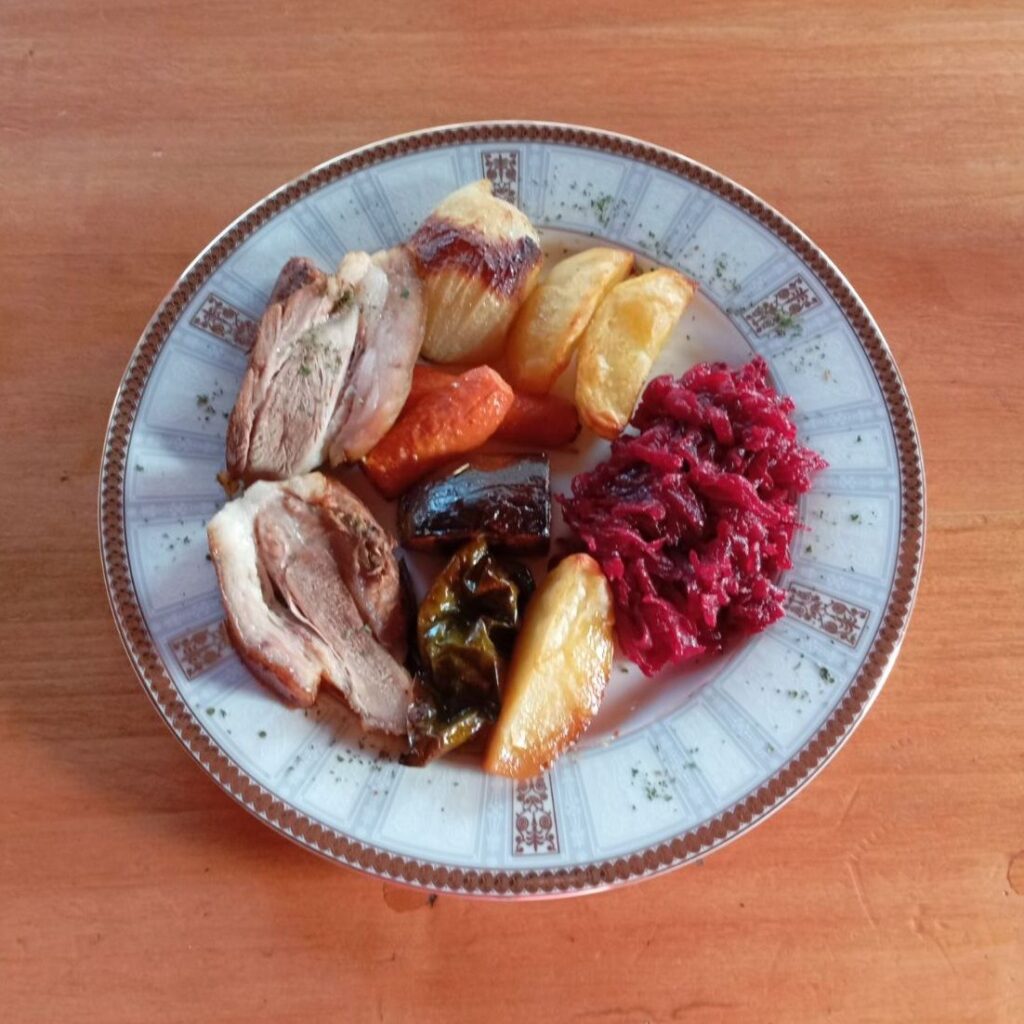 Roasted Pork Veggie Plate served with sliced pork shank, roasted vegetables, and a spoonful of fresh grated beet salad, arranged in an inviting way.