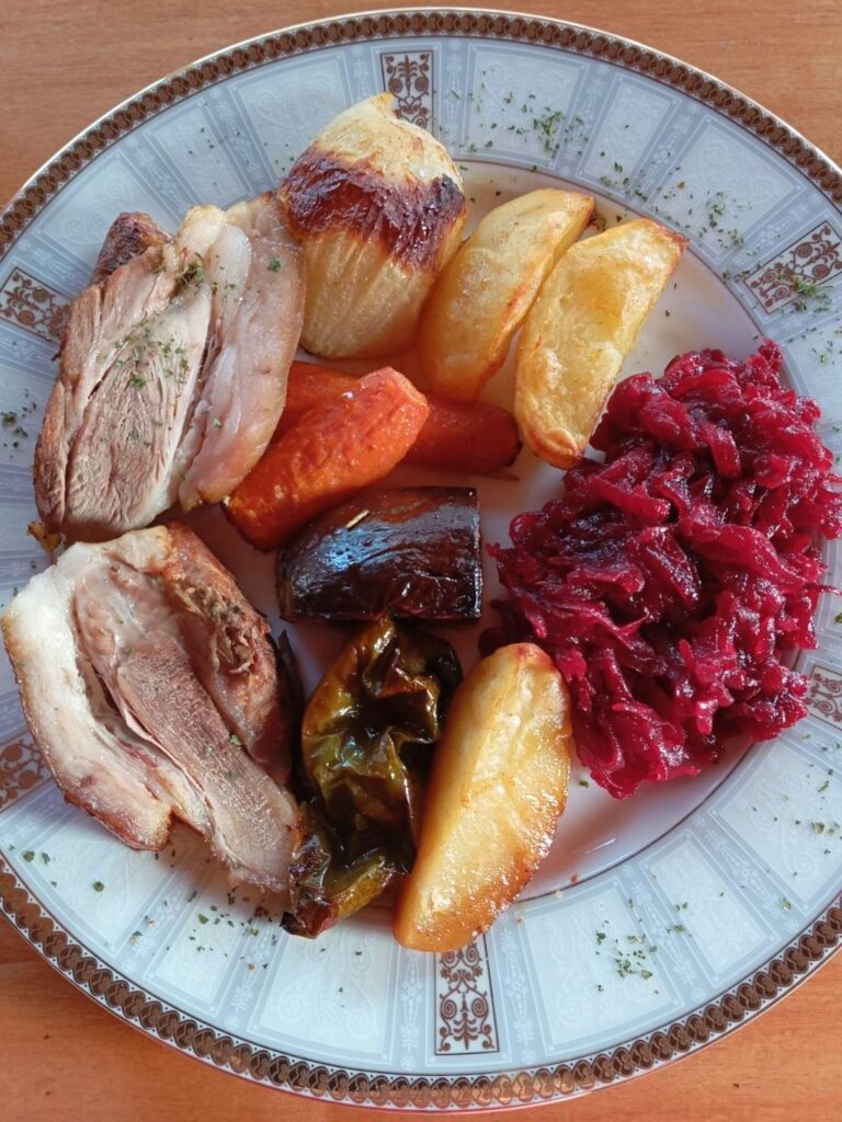 Close-up view of the served Roasted Pork Veggie Plate showing sliced roasted pork, baked vegetables, and fresh grated beetroot salad.