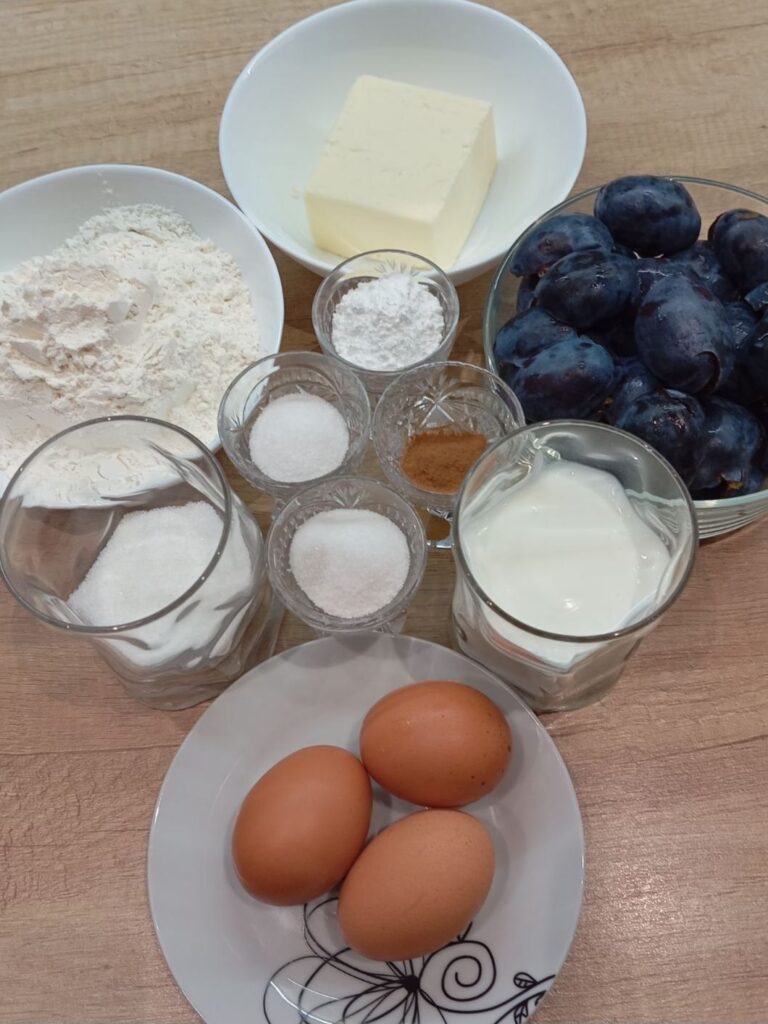All ingredients for our Simple Blue Plum Cake neatly arranged on a kitchen table, ready for preparation.