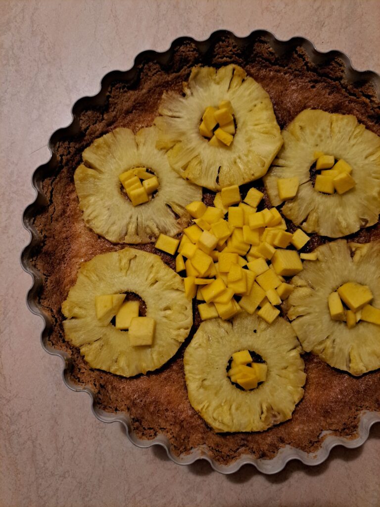 Top view of baked pineapple mango tart with pineapple rings and diced mango arranged in a circular pattern.