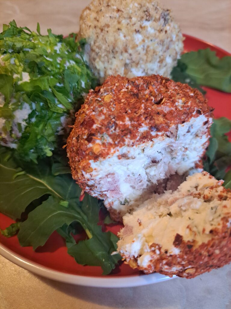 Side view of served cheese meat sunflower balls on fresh arugula, shown close up on a flat plate.