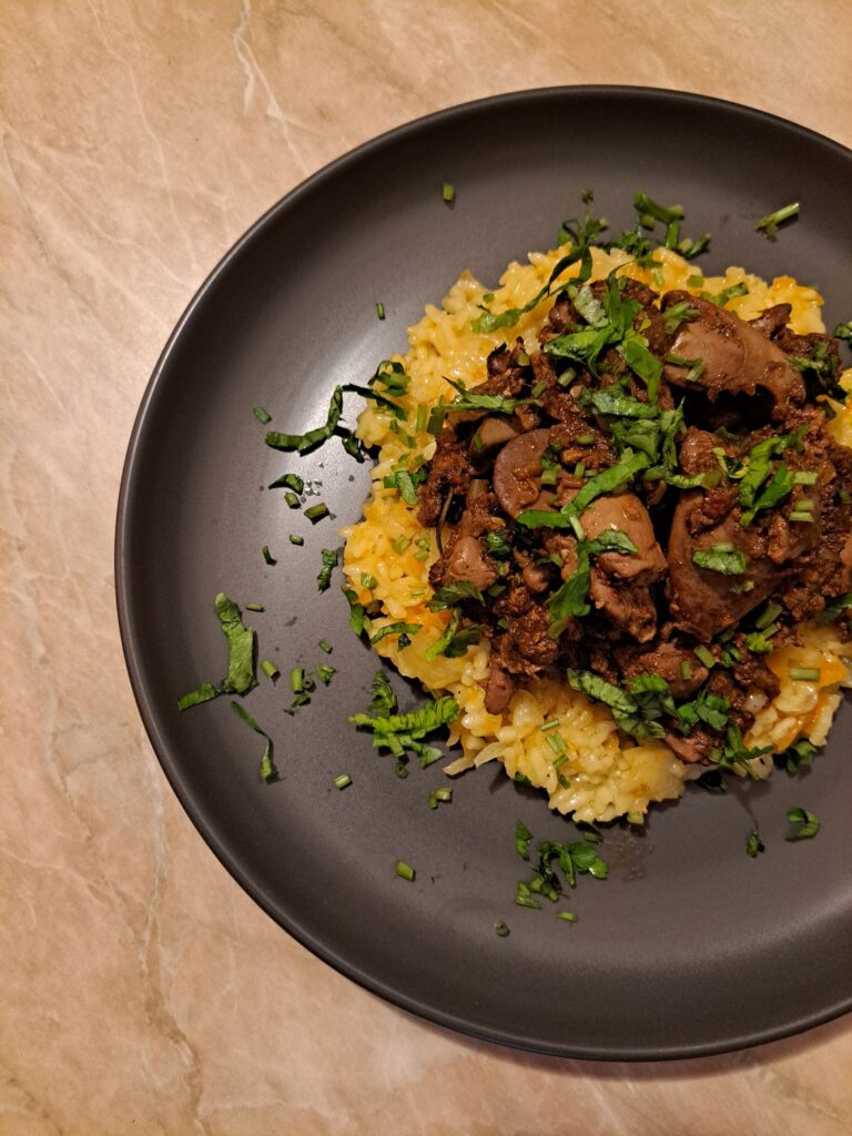 Served plate of braised chicken livers with rice, garnished with fresh parsley.