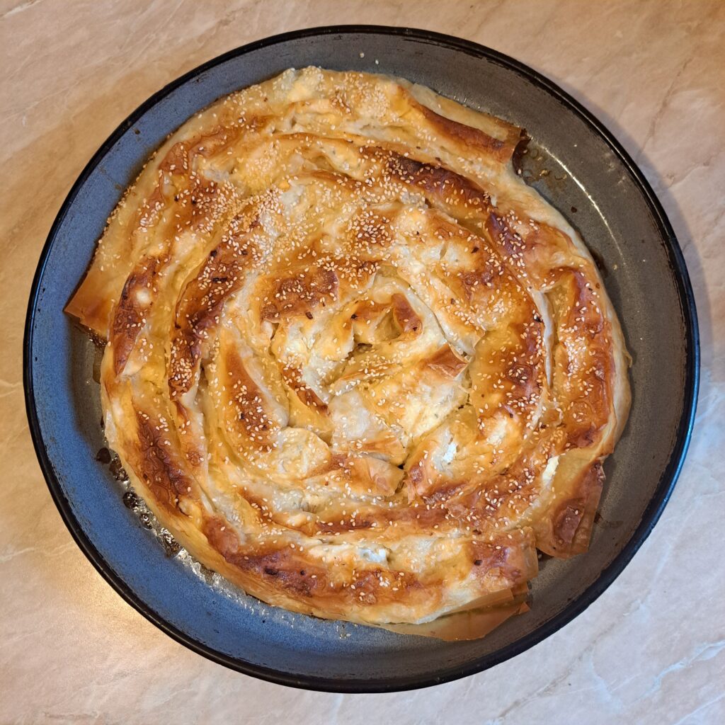 A whole baked pie in a round pan with an evenly golden surface, ready to be sliced and served.