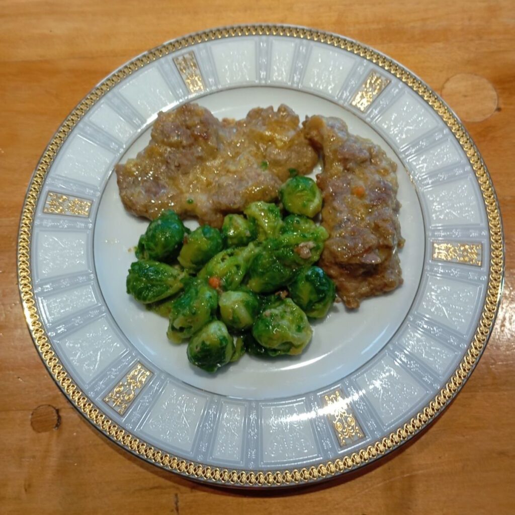 Served portion of Brussels Sprouts Pork Schnitzels on a plate, showing pork schnitzel with Brussels sprouts and light sauce.